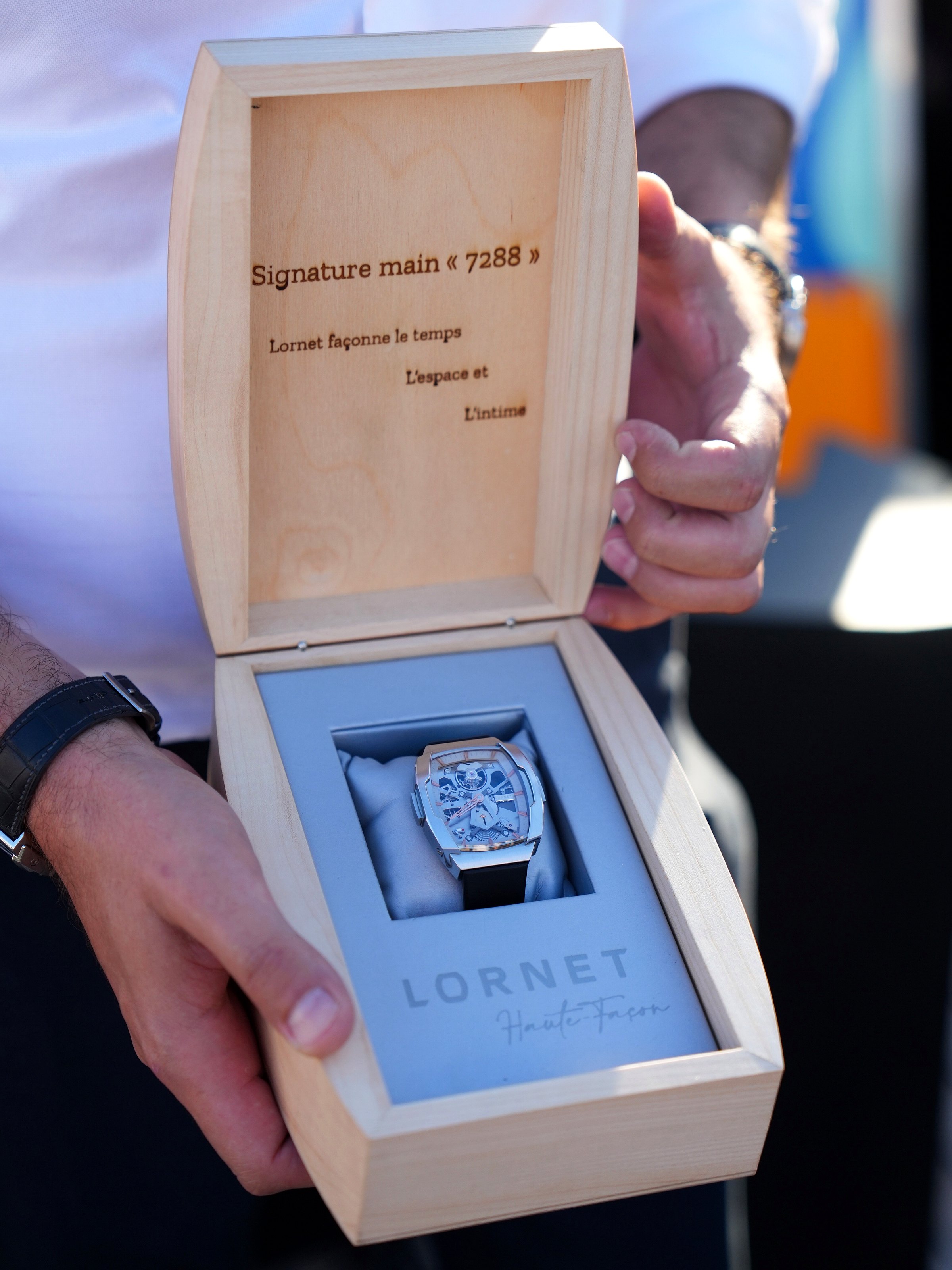A collectible Lornet wristwatch presented in an open wooden box held in two hands